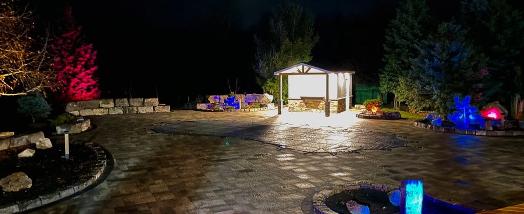 Colour landscape lighting around a stone patio and cabana